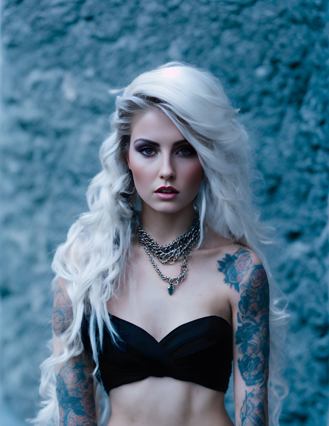 Platinum Blonde Woman with Tattoos and Dark Makeup on Blue Background