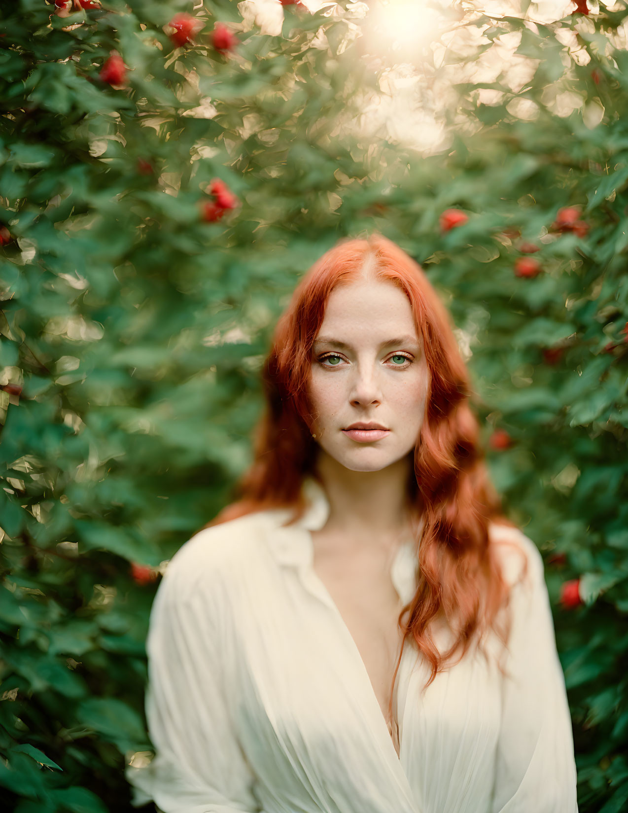 Red-haired woman stands by green bush with red berries