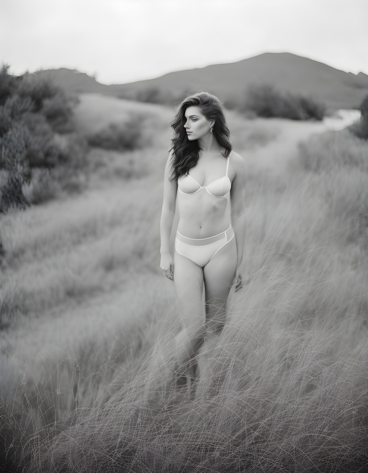 Monochrome photograph of woman in bikini among tall grass