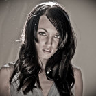 Portrait of woman with deep blue eyes and wavy black hair in snowfall.