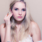 Young woman with blue eyes and red hair posing against beige backdrop