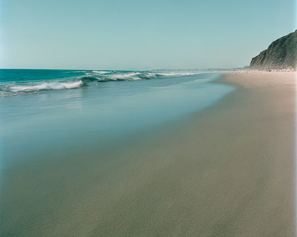 Tranquil Beach Scene with Cliff and Clear Blue Sky
