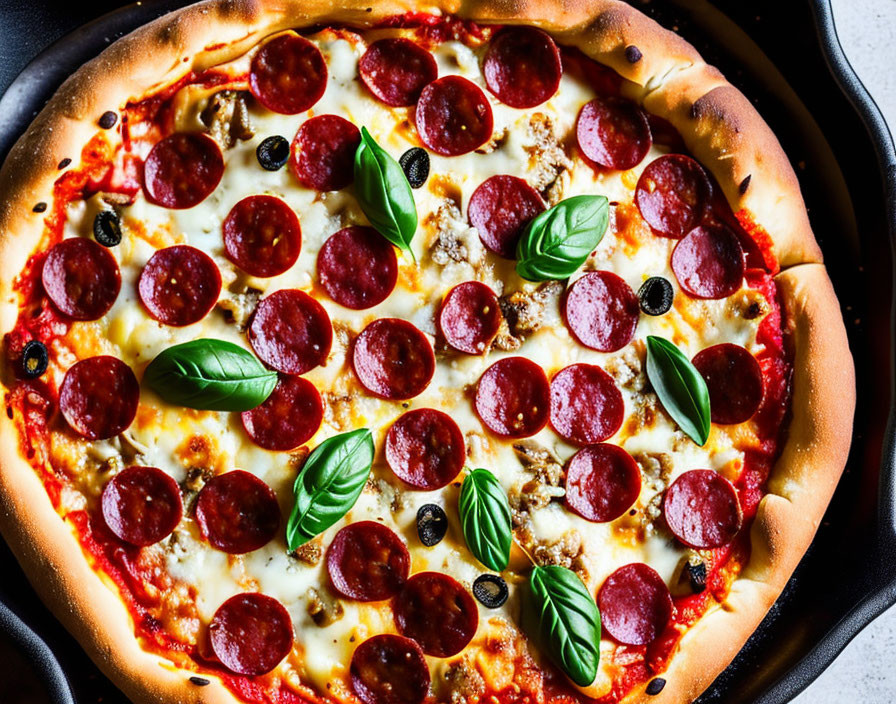 Pepperoni pizza with melted cheese, olives, and basil in a pan