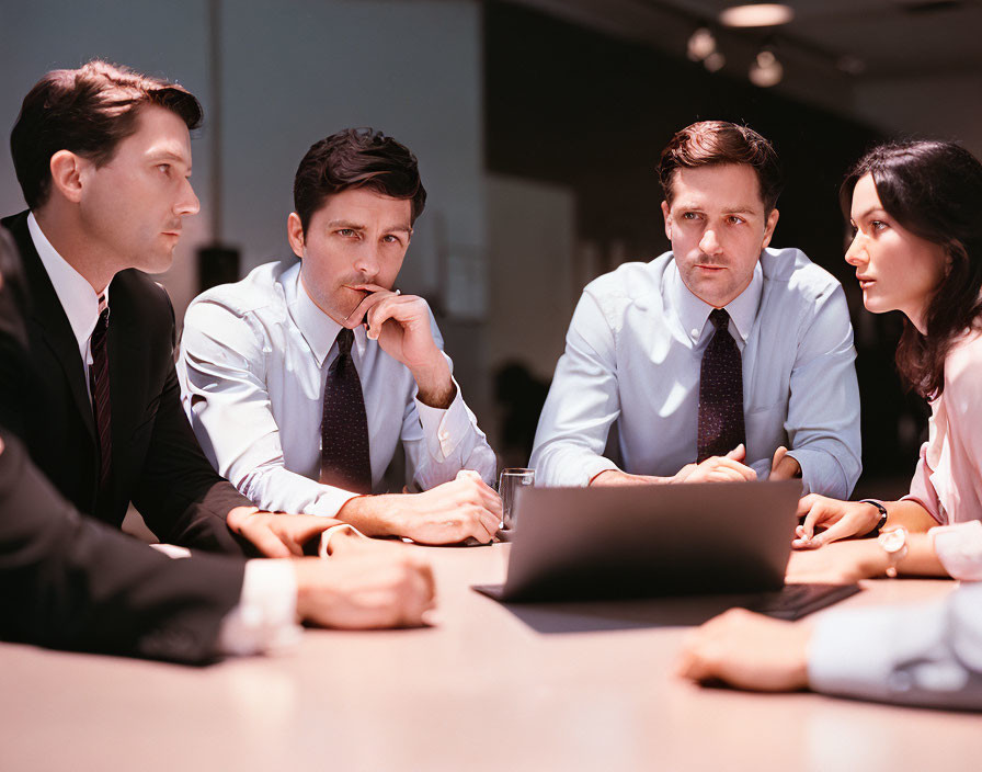 Corporate professionals in a meeting with laptop on table