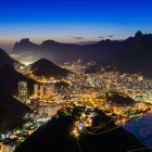 Vibrant nighttime cityscape with futuristic skyscrapers and tower against mountain backdrop