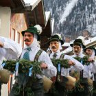 Four jolly dwarves in festive green outfits playing instruments in a snowy scene