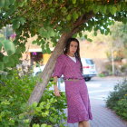 Woman in Purple Floral Dress Under Autumn Tree with Cream Bag