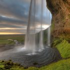 Tranquil fantasy landscape with waterfalls, greenery, flowers, and misty mountains