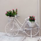 Whimsical white bicycle with vibrant flower baskets on pastel backdrop