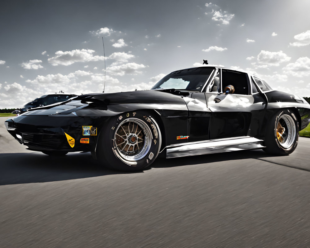 Vintage Black Corvette with Chrome Trim and Aftermarket Wheels on Sunny Day