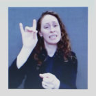 Dark-haired woman in black coat and white blouse, pointing upwards on blue background