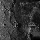 Moon surface with craters, lander, footprints, Earth in background