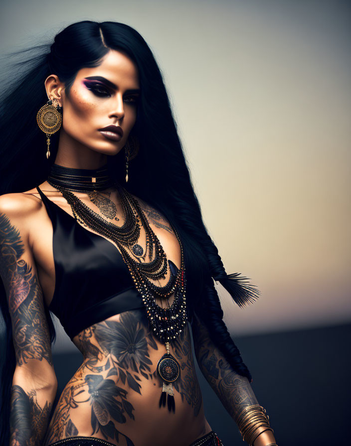 Dark-haired woman with bold makeup, tattoos, and jewelry on neutral backdrop