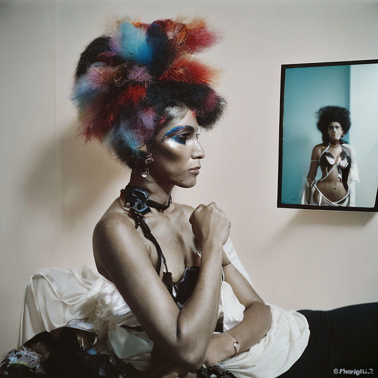 Colorful feather headdress and bold makeup beside framed portrait in neutral room