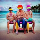 Three men with pink paint splotches on a beach bench, heads edited in bright colors