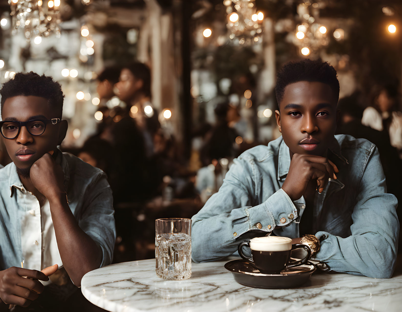 People at cafe table with coffee in cozy setting and blurred lights.