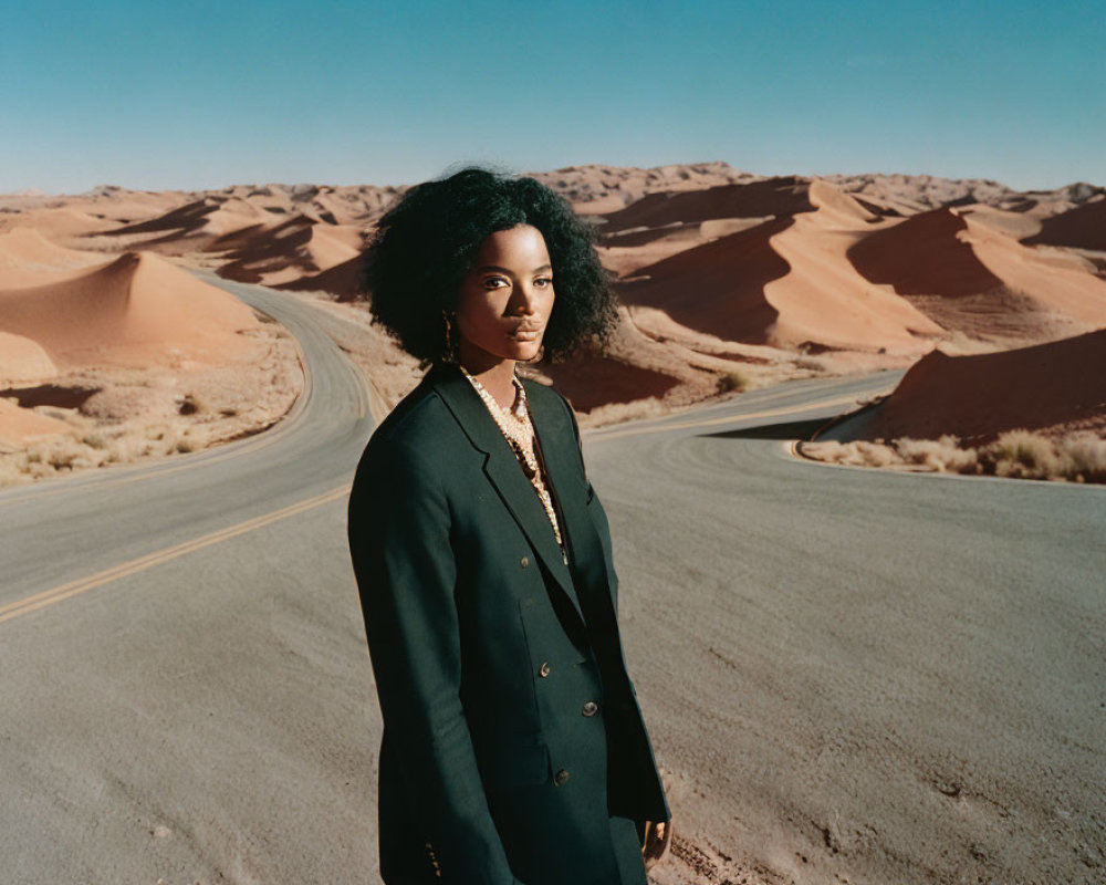 Woman standing on curved desert road under clear blue sky