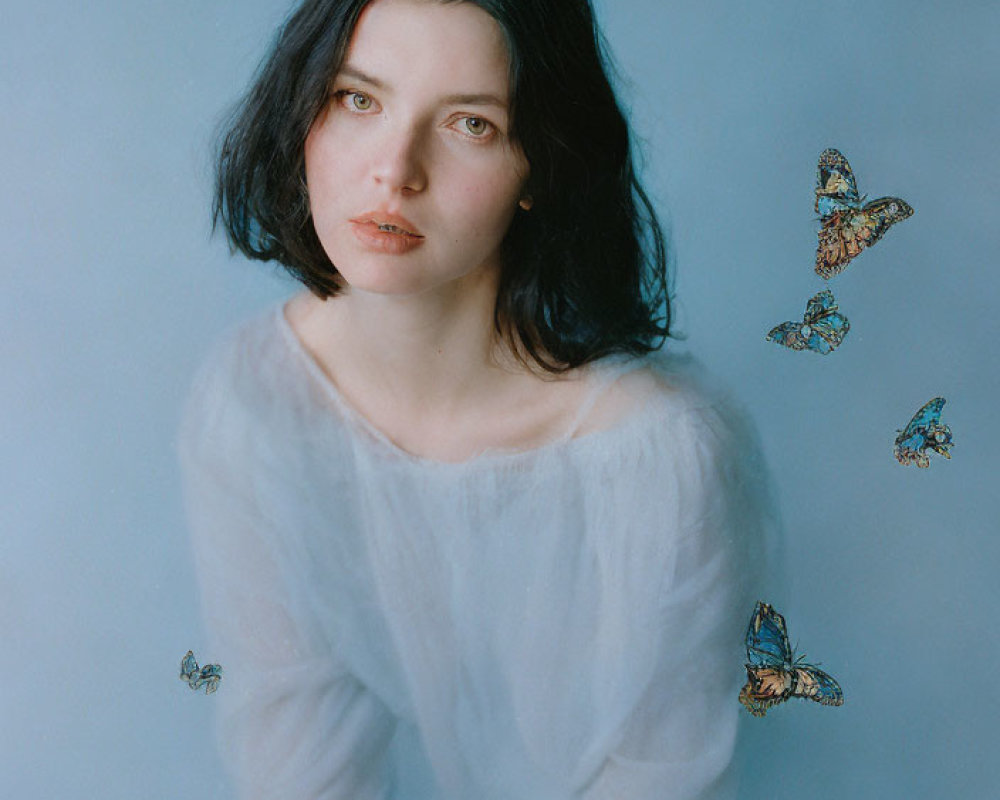 Dark-haired woman in white blouse surrounded by butterflies on blue background