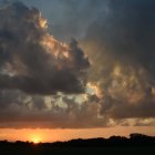 Vibrant sunset with radiant clouds over dark treeline