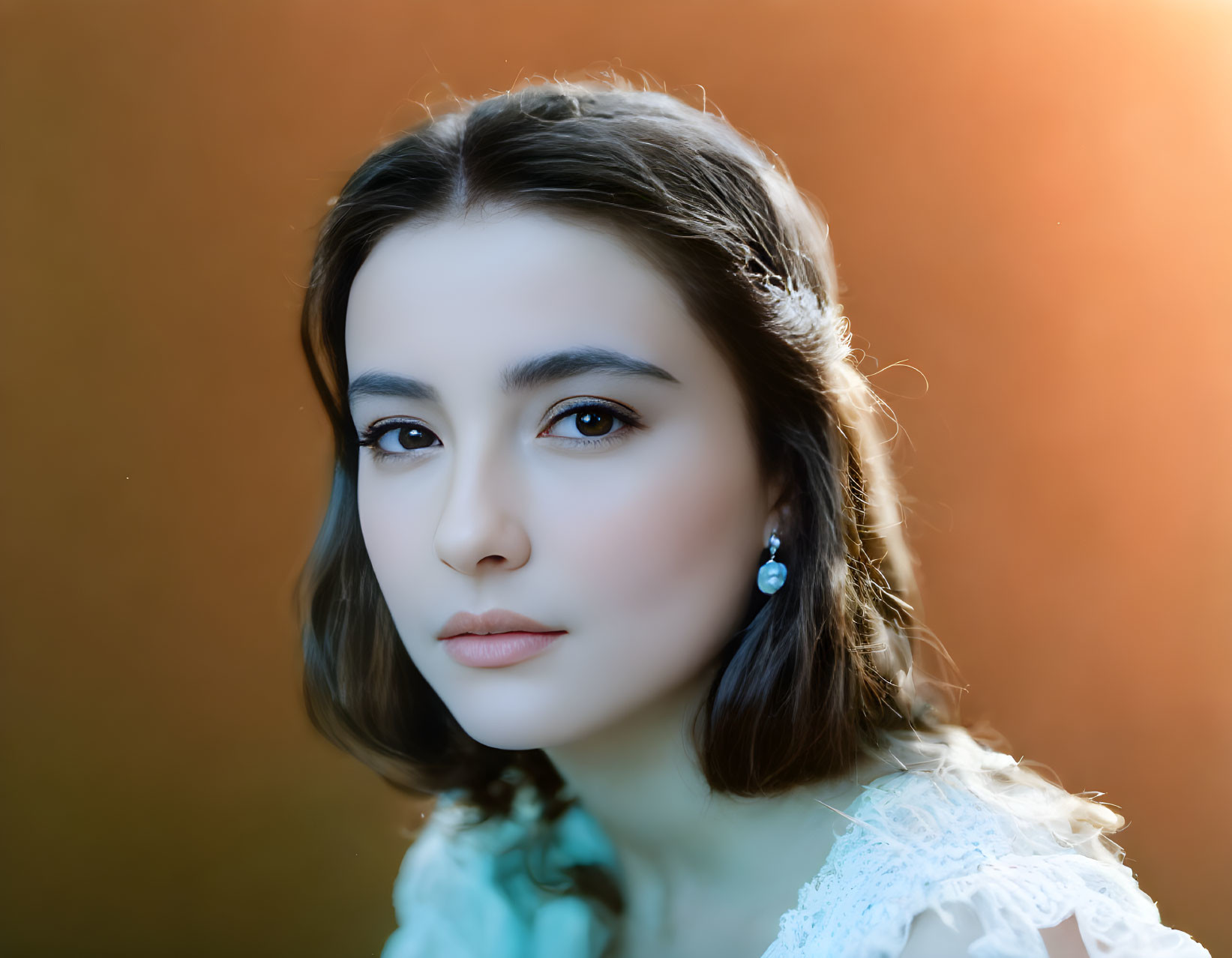 Young woman in white lace dress with pearl earrings on warm-toned background