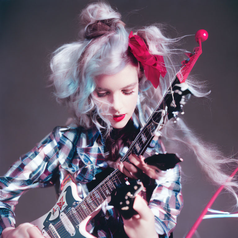 Pastel-haired woman playing electric guitar with red bow on grey background