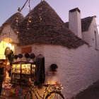 Charming cobblestone street at twilight with traditional white houses and lit lanterns