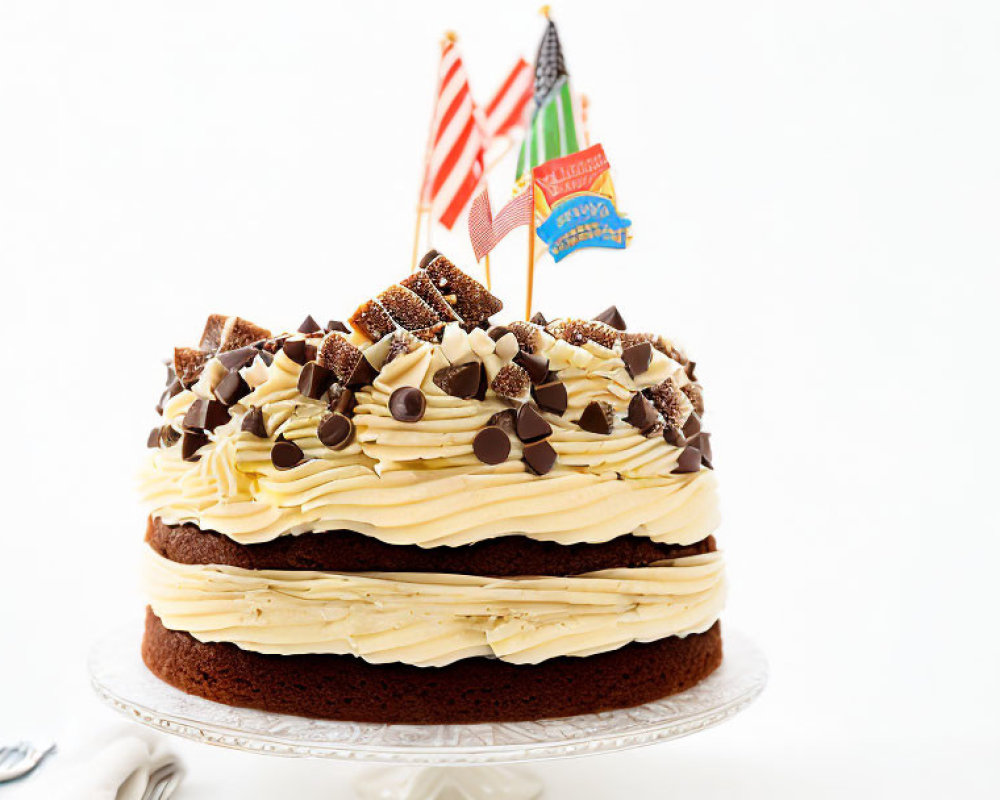 Layered Chocolate Cake with Creamy Frosting and Chocolate Pieces on Glass Stand