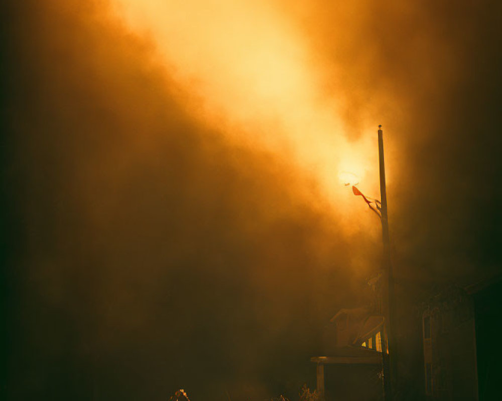 Silhouetted Figure Near House Under Amber Sky with Streetlight and Light Streak