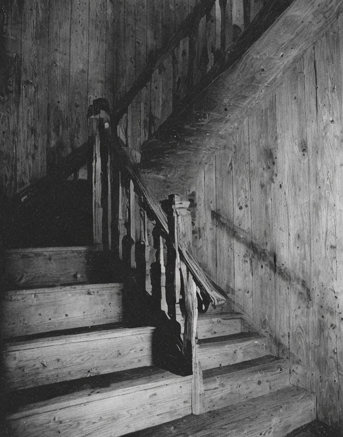 Weathered wooden staircase with balusters in dimly lit setting