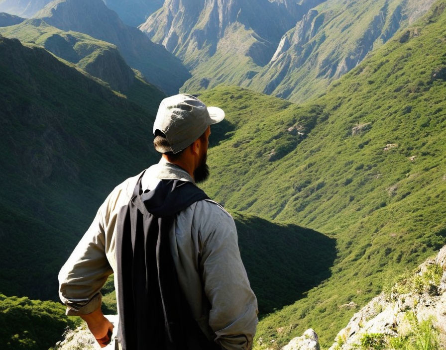 Person in Cap and Jacket Overlooking Lush Green Mountain Valley