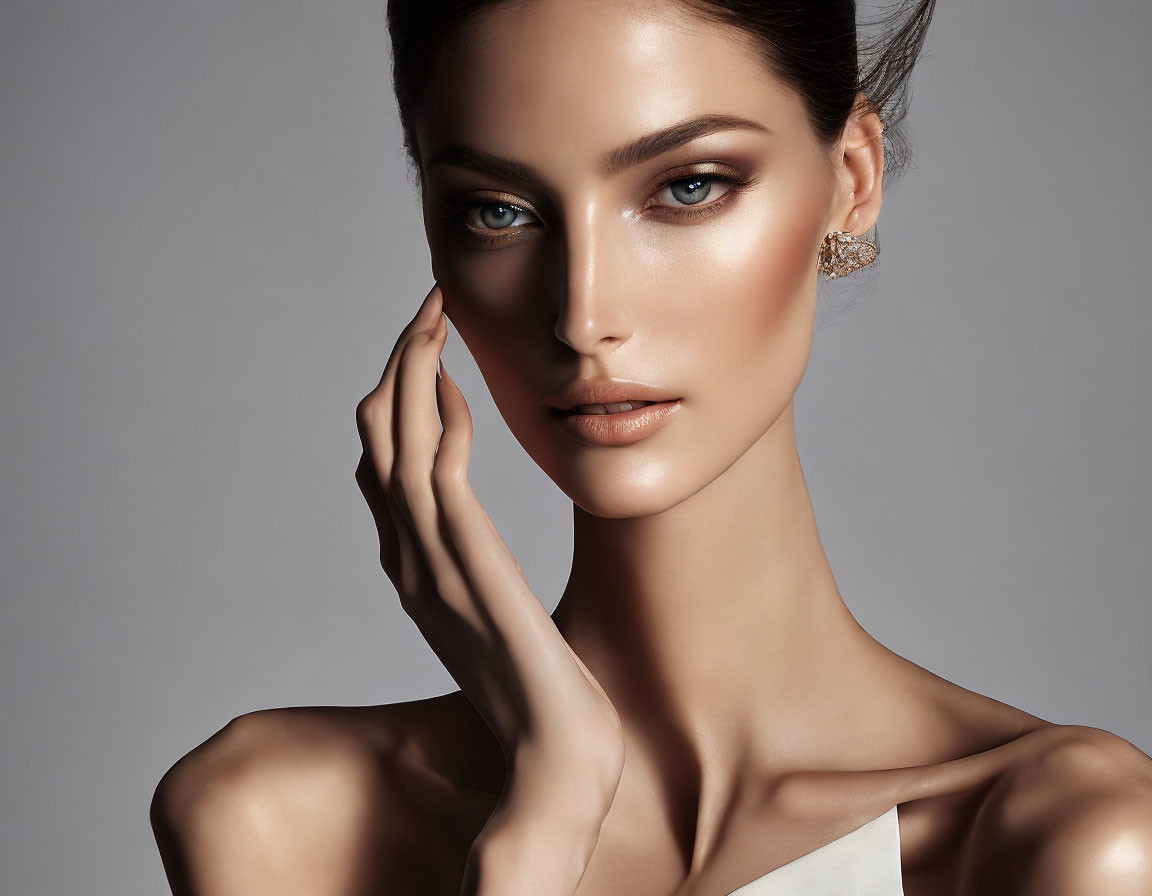 Elegant woman with striking makeup and hand pose in white off-shoulder attire