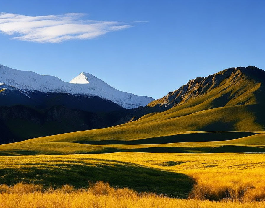 Scenic view of green hills, blue sky, snow-capped mountains, and sun glow