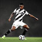 Soccer player in black and white striped kit controls ball on grey background