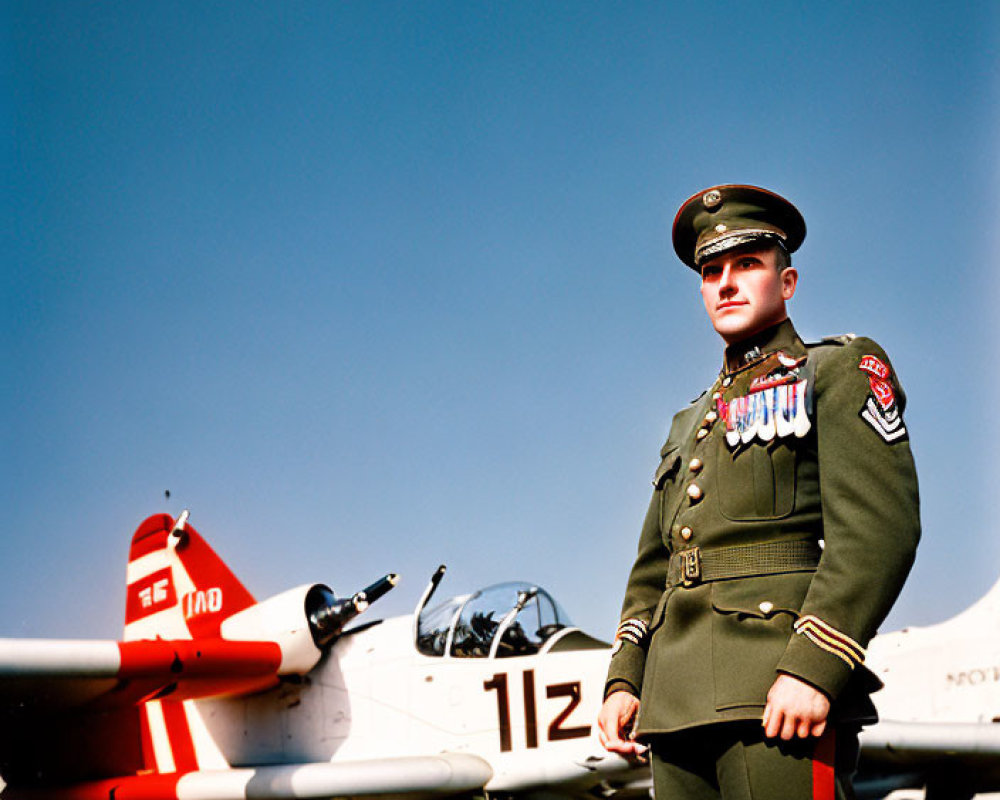 Military officer with medals in front of propeller aircraft under clear blue sky