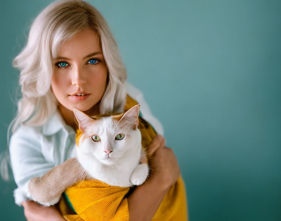 Blonde Woman Holding Orange and White Cat on Teal Background