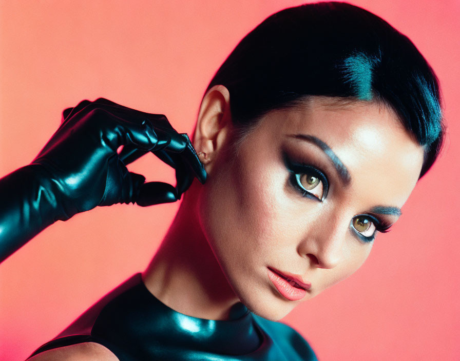 Sleek hairstyle and makeup woman posing with black glove on pink background