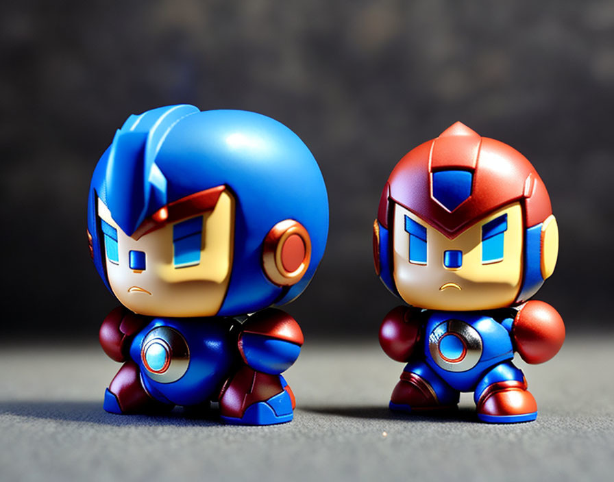 Stylized Mega Man and Proto Man figurines in blue and red with oversized heads on gray background