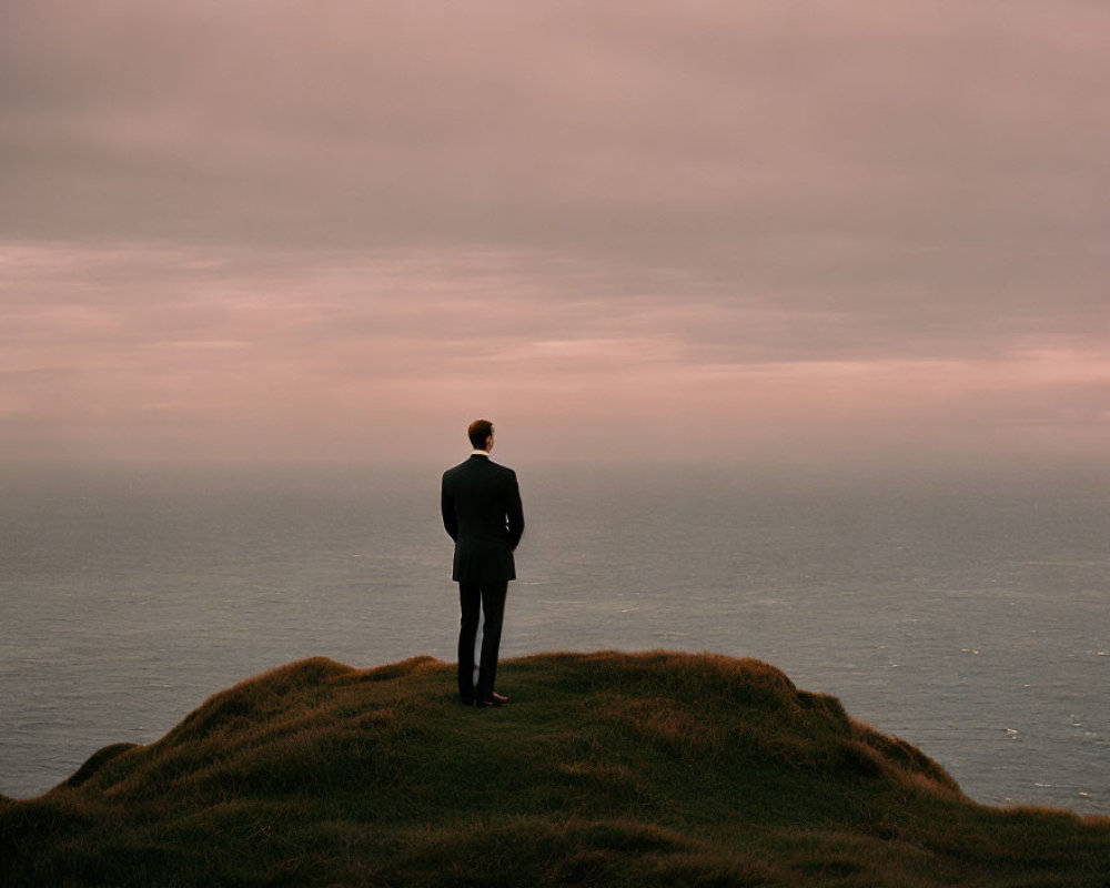 Person in Dark Suit Contemplating Sea View at Dusk