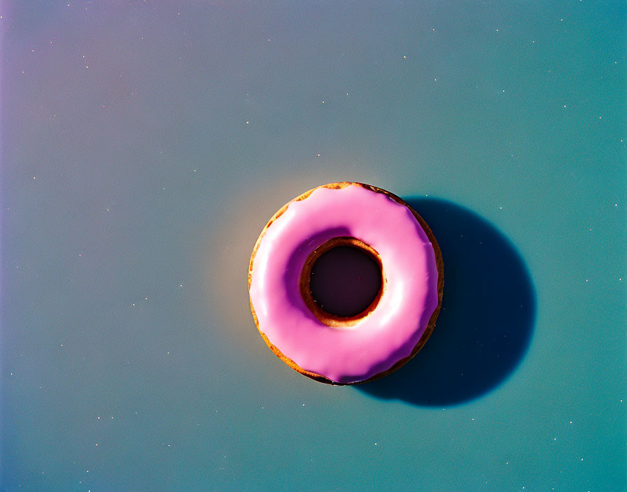 Pink Frosted Donut on Blue Surface with Star Speckles