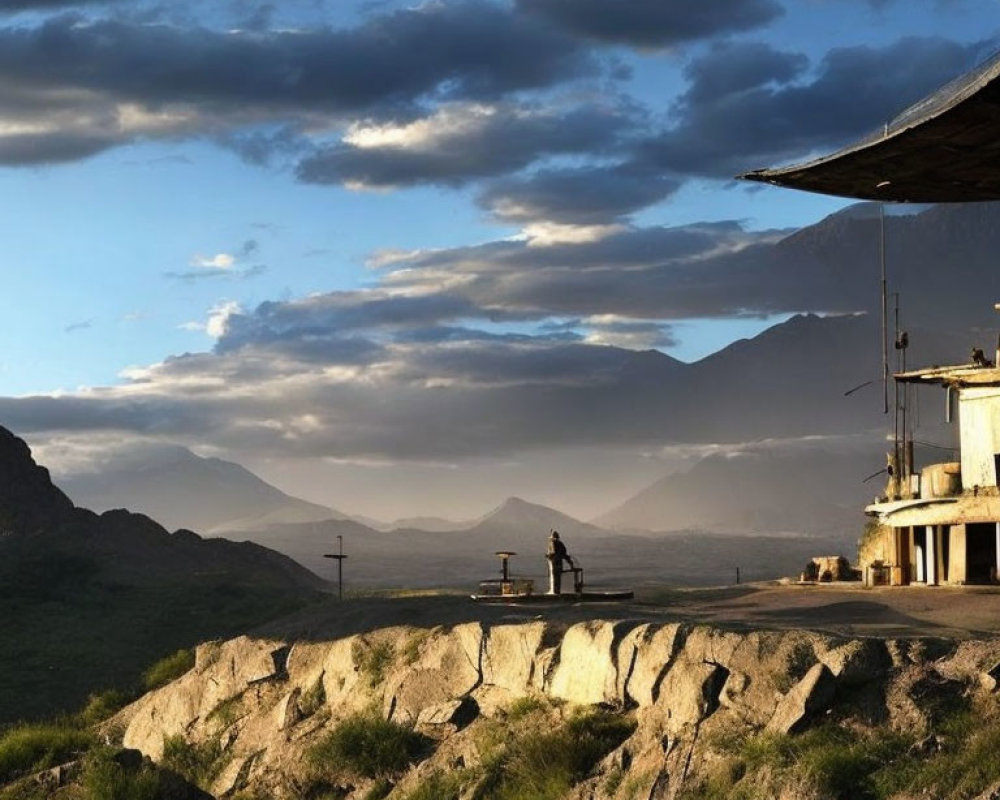 Serene landscape with two individuals on rocky outcrop overlooking mountains at dusk