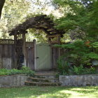 Intricate garden gate leading to lush flower-lined path in village setting