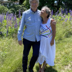 Man in suit and hat embraces woman in lilac dress in starry forest scene