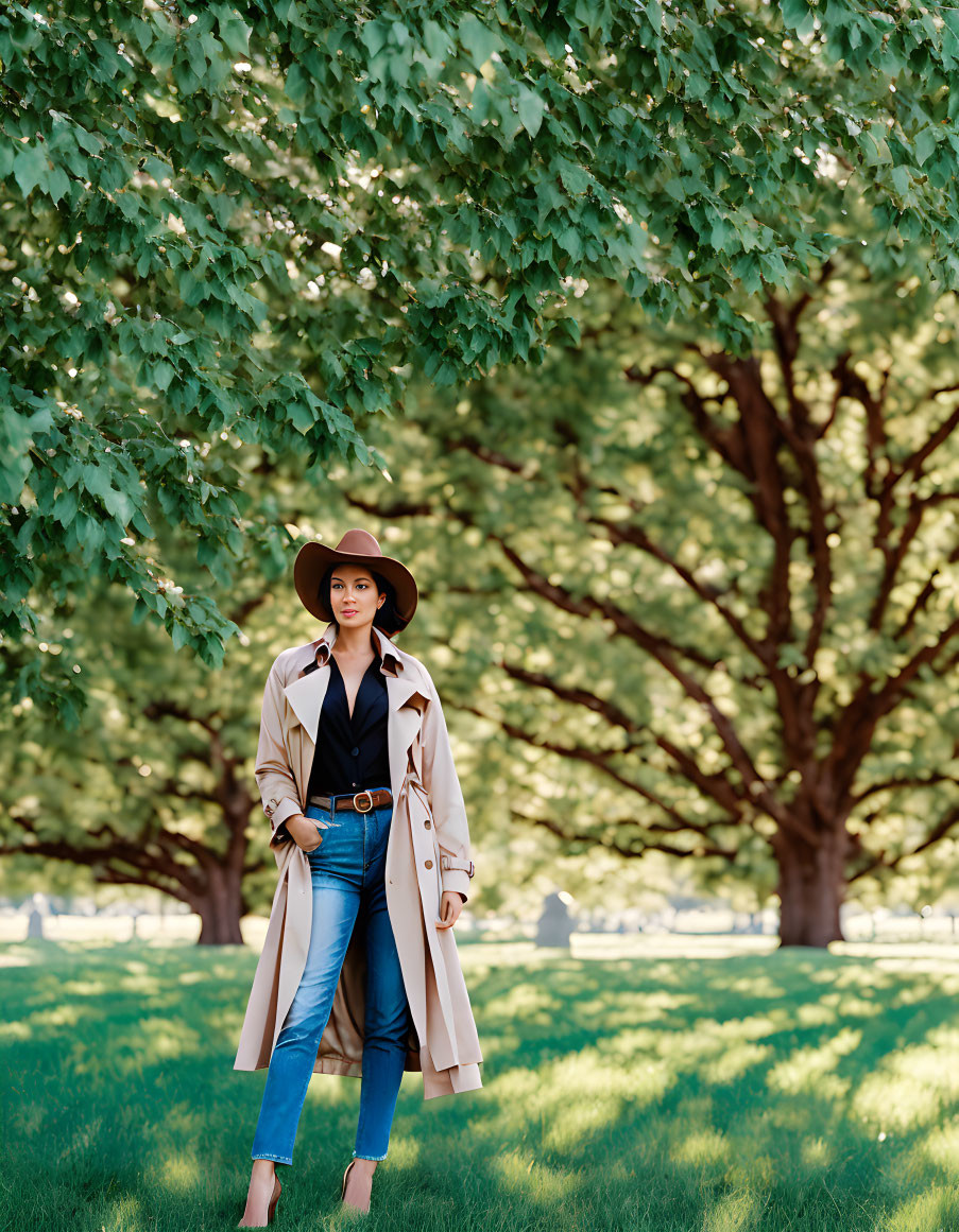 Fashionable person in trench coat under green trees