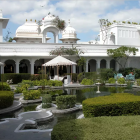 Fantastical palace with pink and white spires in lush garden setting.