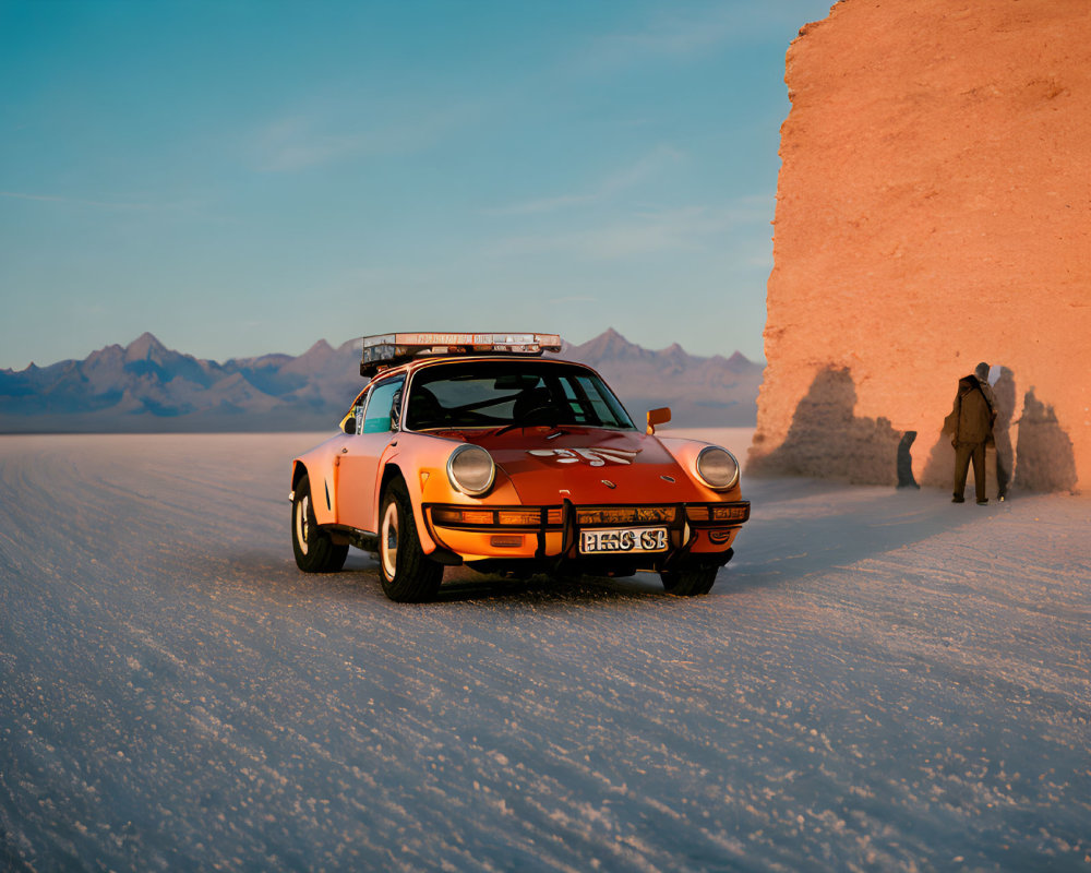 Orange Vintage Sports Car on Salt Flat Terrain at Sunset with Mountains and Person Walking Towards Salt Formation