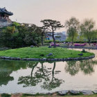 Tranquil Asian garden at dusk with pavilions, pond, and blooming flowers