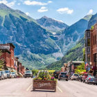 Snowy Mountain Village Painting with Vintage Cars and People in Warm Clothing