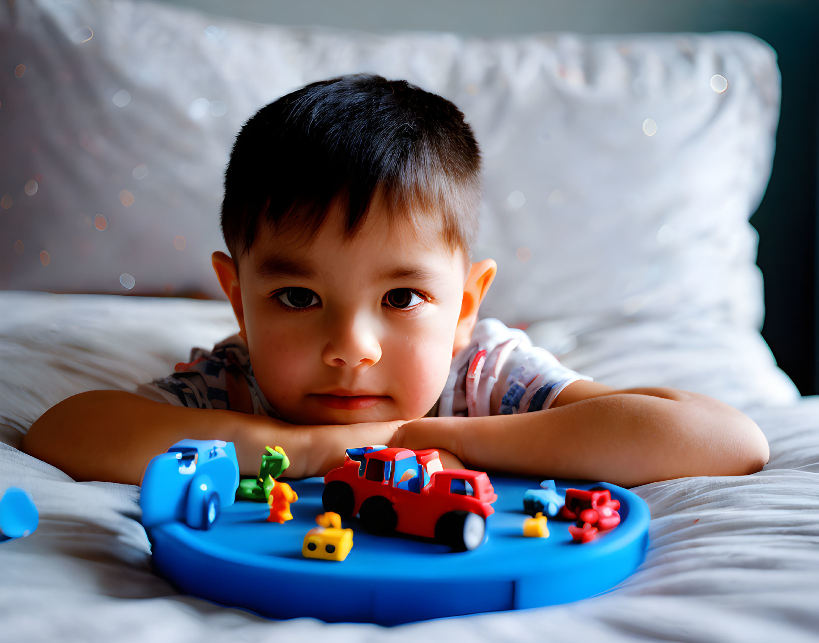 Child playing with colorful toy cars on blue track.