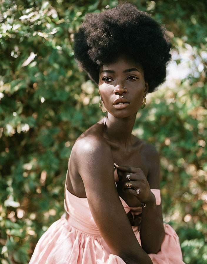 Striking Afro hairstyle on woman in pink dress and gold earrings