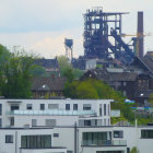 Futuristic cityscape with greenery, modern white buildings, and industrial structures under a hazy